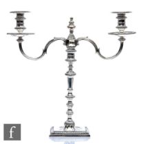 A hallmarked silver twin light cast candelabra, square base with gadroon detail to border below