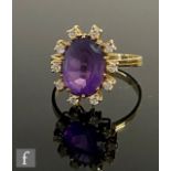 An 18ct amethyst and diamond cluster ring, central oval amethyst, length 12mm, within a ten stone