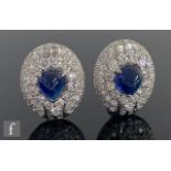 A pair of sapphire and diamond 18ct white gold oval cluster stud earrings, central cabochon sapphire