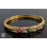 An 18ct hinged bangle set with sapphire, ruby, emerald four stone clusters spaced by diamond set C