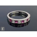 An 18ct hallmarked ruby and diamond nine stone half eternity ring, alternating stones to a plain