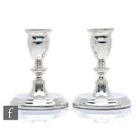 A pair of hallmarked silver piano candlesticks, circular bases below knop columns and conforming