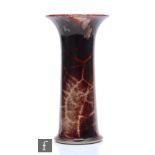 A Ruskin Pottery high fired lily vase of flared form decorated with a deep red with lavender and