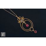 An Edwardian 9ct seed pearl and two red stone open work pendant suspended from a fine trace chain,
