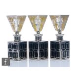 A set of three silver overlaid square sectioned scent bottles each with a black glass body below a