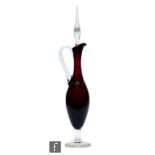 A 1950s Italian glass decanter of ewer form, the deep purple body raised to a clear foot, with