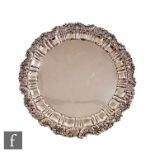 A hallmarked silver circular salver raised on three scroll feet and terminating on pie crust and