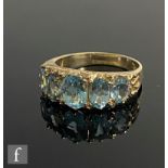 A 9ct hallmarked Victorian style graduated five stone blue topaz ring to scroll shoulders, weight