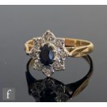 An 18ct hallmarked sapphire and diamond cluster ring, central oval sapphire to an illusion set