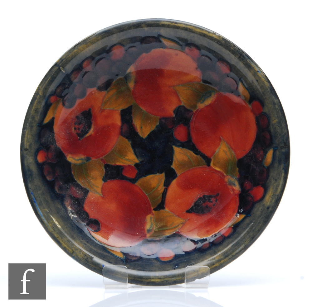 A Moorcroft shallow dish plate decorated in the Pomegranate pattern with open and whole fruits and