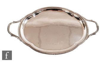 A hallmarked silver twin handled shaped oval tray of plain form terminating in gadroon decorated
