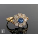 An 18ct hallmarked sapphire and diamond daisy cluster ring, central sapphire within a border of