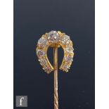 An early 20th Century diamond set horseshoe stick pin, comprising nine old cut, claw set stones,