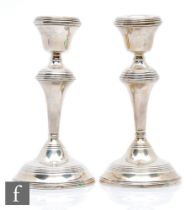 A pair of hallmarked silver candlesticks, each with reeded decoration to circular bases, knops and