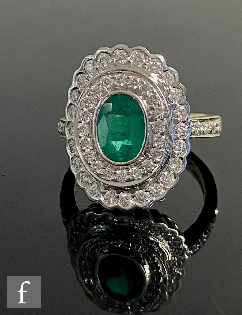 A modern 18ct hallmarked emerald and diamond cluster ring, central oval, collar set emerald,