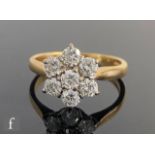An 18ct hallmarked diamond daisy cluster ring comprising seven claw set brilliant cut stones,