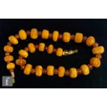 A graduated single row of butterscotch flat cylindrical amber beads spaced by faceted citrene