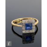An early 20th 18ct Century sapphire and diamond cluster ring, central square facet cut sapphire