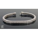 An 18ct hallmarked diamond tennis bracelet comprising approximately seventy princess cut channel set