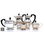 A hallmarked silver five piece pedestal tea set of plain form with reeded details, the three pots