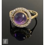 A 9ct hallmarked amethyst and diamond halo ring, central cabochon collar set amethyst within a