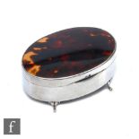 A hallmarked silver oval trinket box with tortoiseshell panel to hinged cover, all raised on four