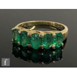 A modern 9ct emerald five stone ring, claw set oval stones to plain tapering shoulders, weight 3.4g,