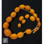 A single row of sixteen butterscotch amber beads, largest bead length approximately 24mm, with