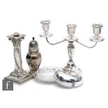 Four items of hallmarked silver, three light squat candelabra, a circular butter dish and cover, a