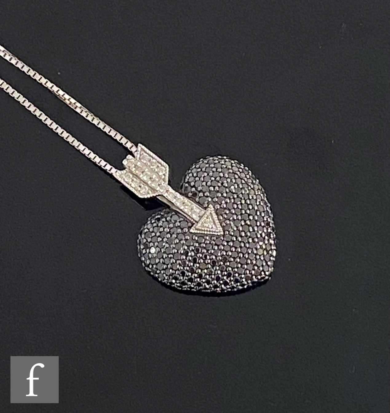 A modern 18ct white gold black and white diamond set pendant modelled as a black heart below a white