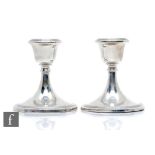 A pair of hallmarked silver piano candlesticks each with reeded detail to circular foot and