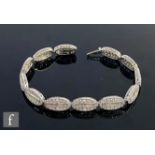 An 18ct hallmarked white gold diamond bracelet comprising twelve oval panels each with a central row