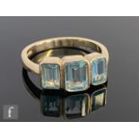 A 9ct hallmarked blue topaz three stone ring, emerald cut collar set stones to knife edged