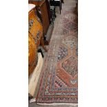 An attractive antique Middle Eastern woollen Carpet Runner,  the central panel on claret ground with