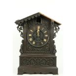 A German carved wooden Cuckoo Clock, Black Forest with arched top and circular dial with Roman