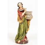 An early polychrome decorated carved wooden Figure, of a standing Saint, holding a book and quill