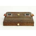 A late 19th Century carved Burmese wooden Desk Stand, with two ink bottles, two pen slots and a