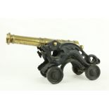 A heavy brass Floor Cannon, on cast iron dragon form carriage and four cast iron wheels, 18" (