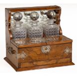 A fine silver mounted and figured walnut Tantalus, with three square cutglass decanters with prism