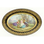 A large oval Serves style porcelain Platter, depicting three figures in a garden landscape, inside a