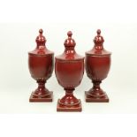 A set of 3 large burgundy ground ceramic Urns and Covers, each on square stem base. (3)