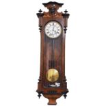 A 19th Century walnut Vienna Wall Clock, the capital with carved female face in relief over arched