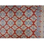 An unusual 20th Century woollen Carpet, the red ground with multiple lozenge centre, the border with