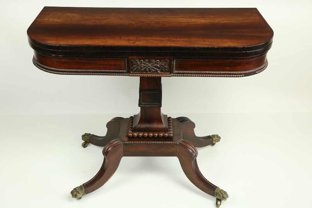 A Regency period rosewood fold-over Card Table, the bead moulded frieze with a centre panel carved