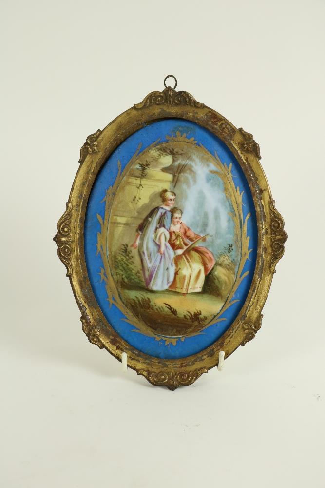 An oval Sevres style porcelain Plaque, c. 1900, decorated with two Ladies in a garden, inside a