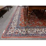 A large Middle Eastern style red ground floral decorated woollen Carpet, with conforming fawn ground