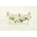 A Sitzendorf porcelain flower encrusted Table Centre, c. 1900, modelled with two cherubs