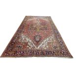 A Persian Heriz Carpet, the iron red field with a centre medallion and all over pattern with ivory