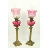 A very good near pair of brass Corinthian style Oil Lamps, each with ruby glass oil reservoir and