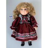 Modern dressed doll with red velvet dress. Ceramic head/arms/legs. Inset still eyes, eyelashes, soft